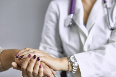 Kadın doktor hastayı sakinleştirir ve elini tutar