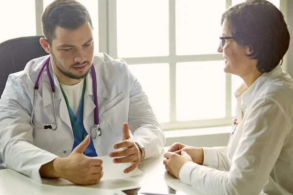 Mladý doktor mluví s pacientem v kanceláři — Stock fotografie