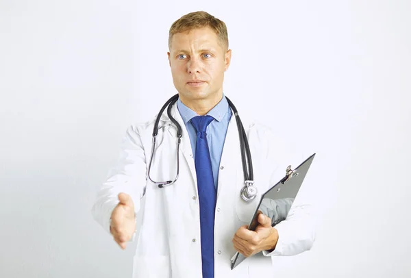 Young doctor in white coat with a stethoscope greets holding out his hand — Stock Photo, Image