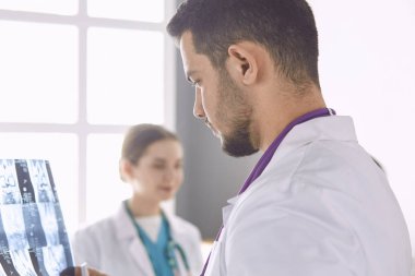 Doktor yaşlı bir kadının röntgen filmini izliyor.