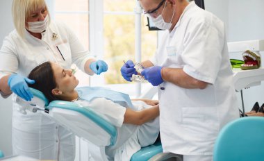 Doktor dişçi genç ve güzel bir kızın dişlerini tedavi ediyor. Dişçinin resepsiyonundaki kız. Doktor dişçi dişleri tedavi eder.