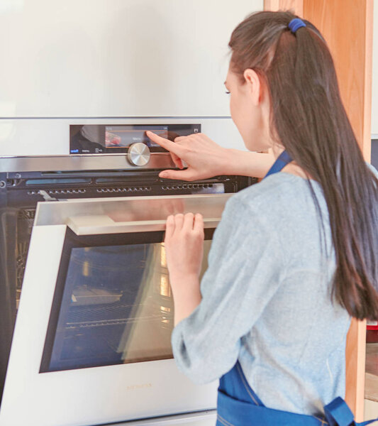 Beautiful woman in the kitchen, waiting with the front of the oven
