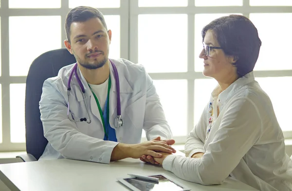 Mladý doktor mluví s pacientem v kanceláři — Stock fotografie