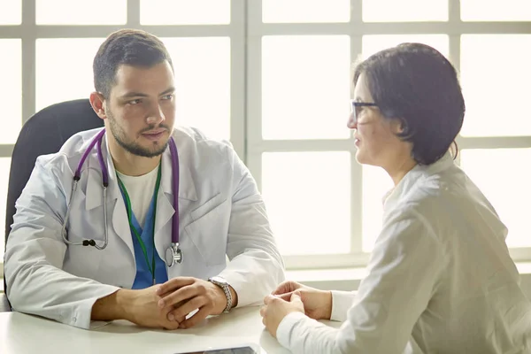 Mladý doktor mluví s pacientem v kanceláři — Stock fotografie