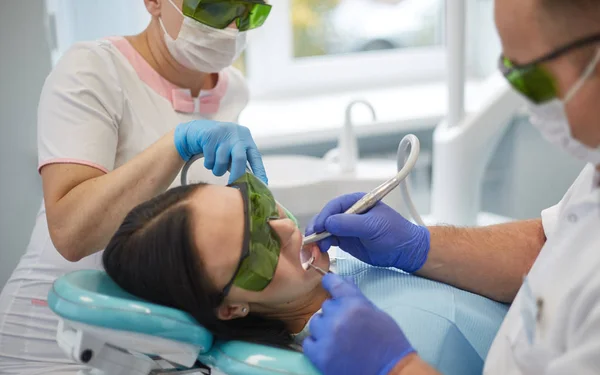 Doctor dentist treats teeth of a beautiful young girl patient. The girl on reception at the dentist. Doctor dentist treats tooth — Stock Photo, Image