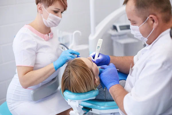 Médico dentista trata os dentes de uma bela jovem paciente. A rapariga na recepção do dentista. Médico dentista trata dente — Fotografia de Stock