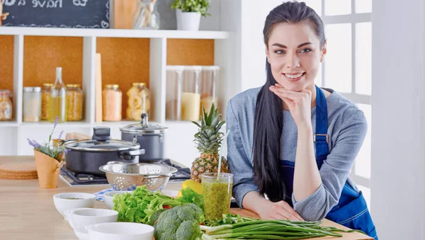 テーブルの上の新鮮な野菜とキッチンで幸せな若い女 — ストック写真