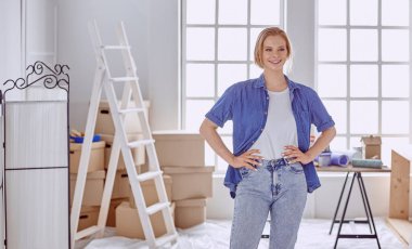 Beyaz tahta bir merdiven üzerinde güzel bir genç kadın. Odayı onarmaya hazırız. Kadın ev işi konsepti