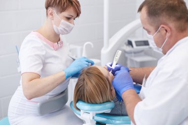 Doktor dişçi genç ve güzel bir kızın dişlerini tedavi ediyor. Dişçinin resepsiyonundaki kız. Doktor dişçi dişleri tedavi eder.