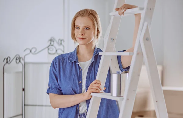 Hermosa joven en una escalera de madera blanca. Listo para reparar la habitación. Concepto de tareas domésticas — Foto de Stock