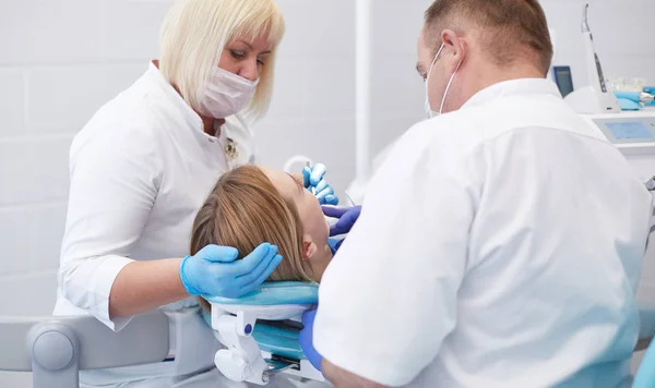 Doctor dentist treats teeth of a beautiful young girl patient. The girl on reception at the dentist. Doctor dentist treats tooth