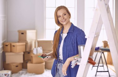 Beyaz tahta bir merdiven üzerinde güzel bir genç kadın. Odayı onarmaya hazırız. Kadın ev işi konsepti