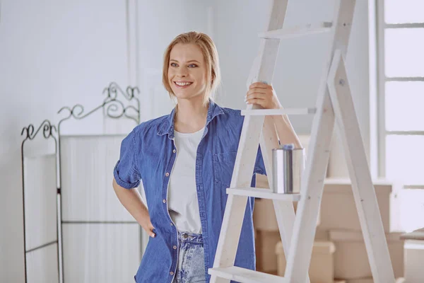 Hermosa joven en una escalera de madera blanca. Listo para reparar la habitación. Concepto de tareas domésticas — Foto de Stock