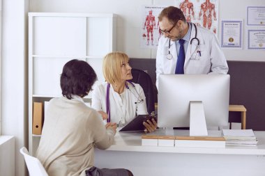 Orta yaşlı erkek doktor bir meslektaşının çalışmasına eşlik ediyor.