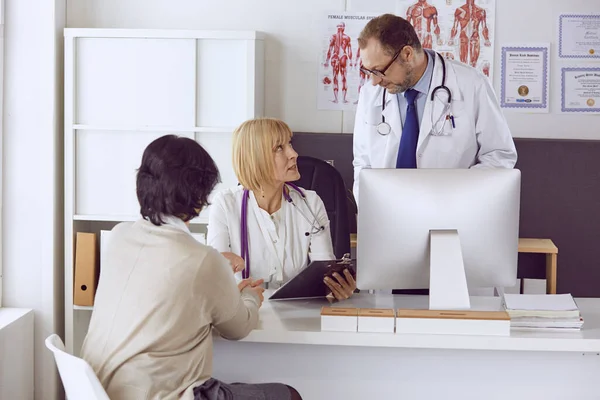 Orta yaşlı erkek doktor bir meslektaşının çalışmasına eşlik ediyor. — Stok fotoğraf