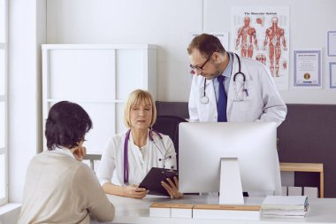 Orta yaşlı erkek doktor bir meslektaşının çalışmasına eşlik ediyor.