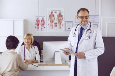 Orta yaşlı erkek doktor bir meslektaşının çalışmasına eşlik ediyor.