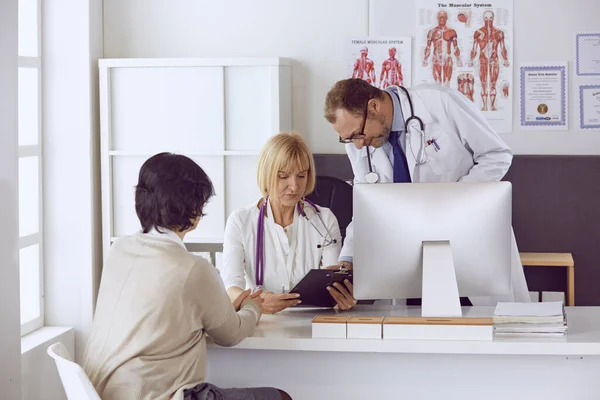 Orta yaşlı erkek doktor bir meslektaşının çalışmasına eşlik ediyor. — Stok fotoğraf