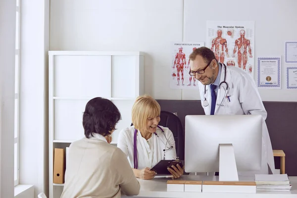 Mannelijke arts van middelbare leeftijd begeleidt het werk van een collega — Stockfoto