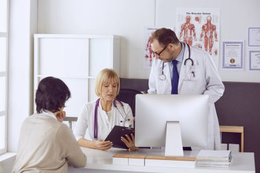 Orta yaşlı erkek doktor bir meslektaşının çalışmasına eşlik ediyor.