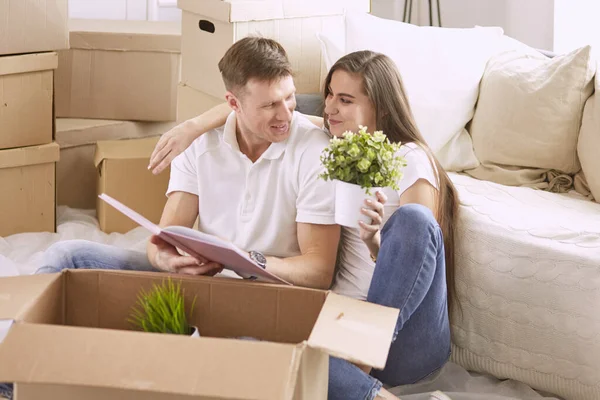 Porträtt av lyckliga par tittar på bärbar dator tillsammans sitter i nytt hus, omgiven av lådor — Stockfoto