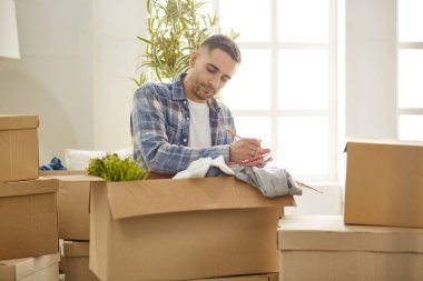 Taşındıktan sonra yeni dairede kutuları olan yakışıklı bir adam.