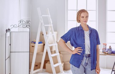 Beyaz tahta bir merdiven üzerinde güzel bir genç kadın. Odayı onarmaya hazırız. Kadın ev işi konsepti