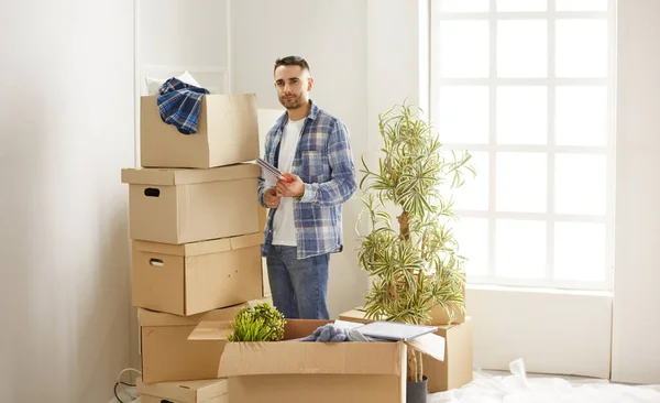 Bonito homem com caixas no novo apartamento depois de se mudar — Fotografia de Stock
