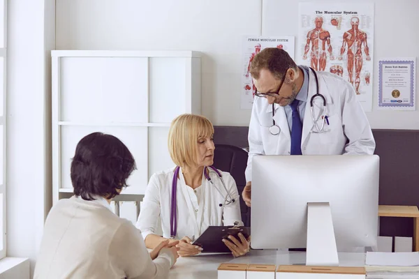 Mannelijke arts van middelbare leeftijd begeleidt het werk van een collega — Stockfoto