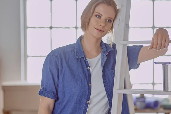 Hermosa joven en una escalera de madera blanca. Listo para reparar la habitación. Concepto de tareas domésticas — Foto de Stock