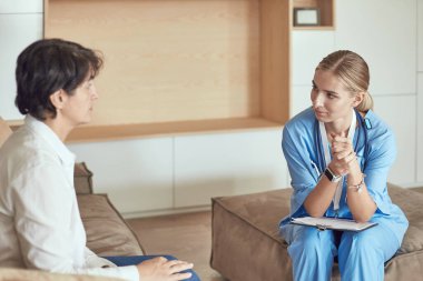 Dost canlısı gülümseyen doktor ve kanepede oturan hasta. Çok