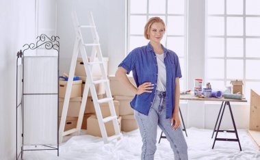 Beyaz tahta bir merdiven üzerinde güzel bir genç kadın. Odayı onarmaya hazırız. Kadın ev işi konsepti