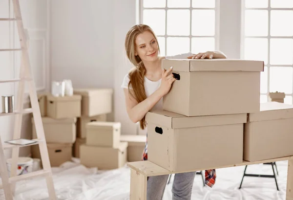 Красивая одинокая девушка распаковывает коробки и переезжает в новый дом — стоковое фото