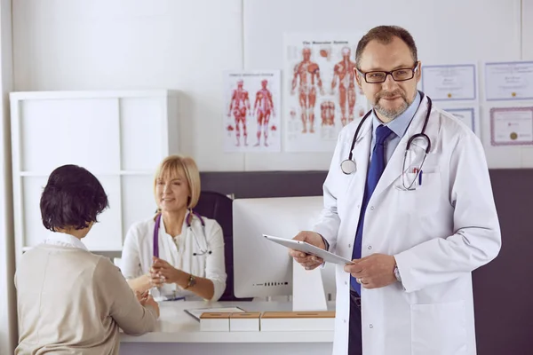 Orta yaşlı erkek doktor bir meslektaşının çalışmasına eşlik ediyor. — Stok fotoğraf