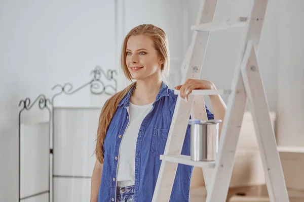 Hermosa joven en una escalera de madera blanca. Listo para reparar la habitación. Concepto de tareas domésticas — Foto de Stock