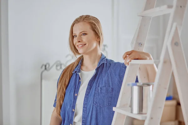 Hermosa joven en una escalera de madera blanca. Listo para reparar la habitación. Concepto de tareas domésticas — Foto de Stock