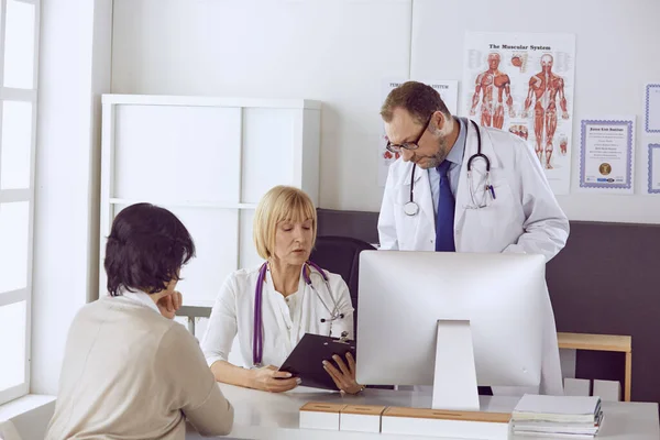 Mannelijke arts van middelbare leeftijd begeleidt het werk van een collega — Stockfoto