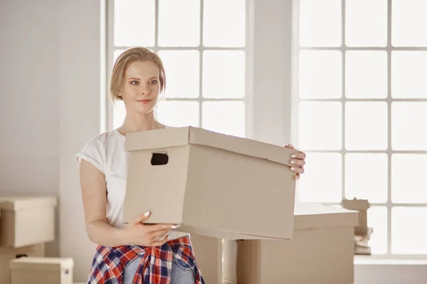 Una hermosa mujer joven soltera desempacando cajas y mudarse a un nuevo hogar —  Fotos de Stock