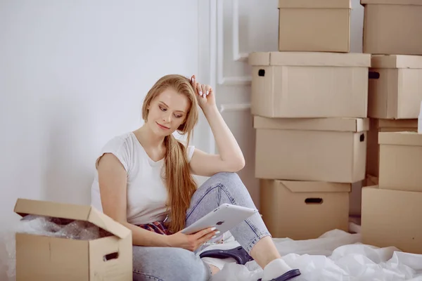 Uma bela mulher solteira desempacotar caixas e se mudar para uma nova casa — Fotografia de Stock