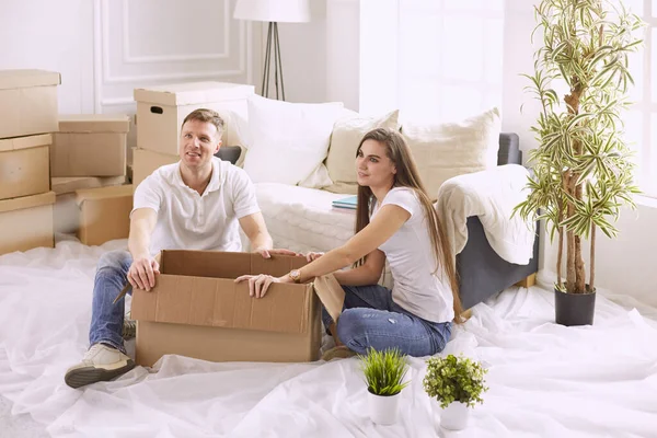 Porträtt av lyckliga par tittar på bärbar dator tillsammans sitter i nytt hus, omgiven av lådor — Stockfoto