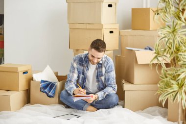 Taşındıktan sonra yeni dairede kutuları olan yakışıklı bir adam.