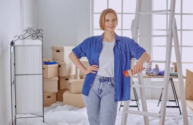 Beyaz tahta bir merdiven üzerinde güzel bir genç kadın. Odayı onarmaya hazırız. Kadın ev işi konsepti