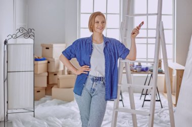 Beyaz tahta bir merdiven üzerinde güzel bir genç kadın. Odayı onarmaya hazırız. Kadın ev işi konsepti