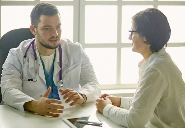 Mladý doktor mluví s pacientem v kanceláři — Stock fotografie