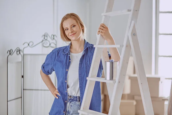 Piękna młoda kobieta na białym drewnianym drabinie. Gotowy do naprawy pokoju. Koncepcja prac domowych dla kobiet — Zdjęcie stockowe