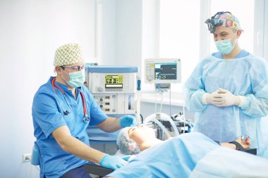 Birkaç doktor hasta operasyon masası üzerinde onların çalışma sırasında çevreleyen. Takım cerrahlar ameliyathane içinde işte