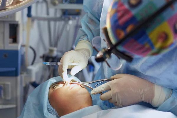 Varios médicos que rodean al paciente en la mesa de operaciones durante su trabajo. Cirujanos de equipo trabajando en quirófano — Foto de Stock