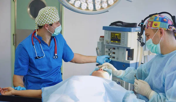 Několik lékařů kolem pacienta na operaci stůl během jejich práce. Tým chirurgů při práci v operačním sále — Stock fotografie