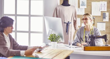 Güzel terzi müşterisine yeni bir tasarım gösteriyor