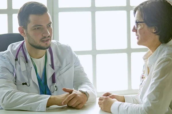 Mladý doktor mluví s pacientem v kanceláři — Stock fotografie